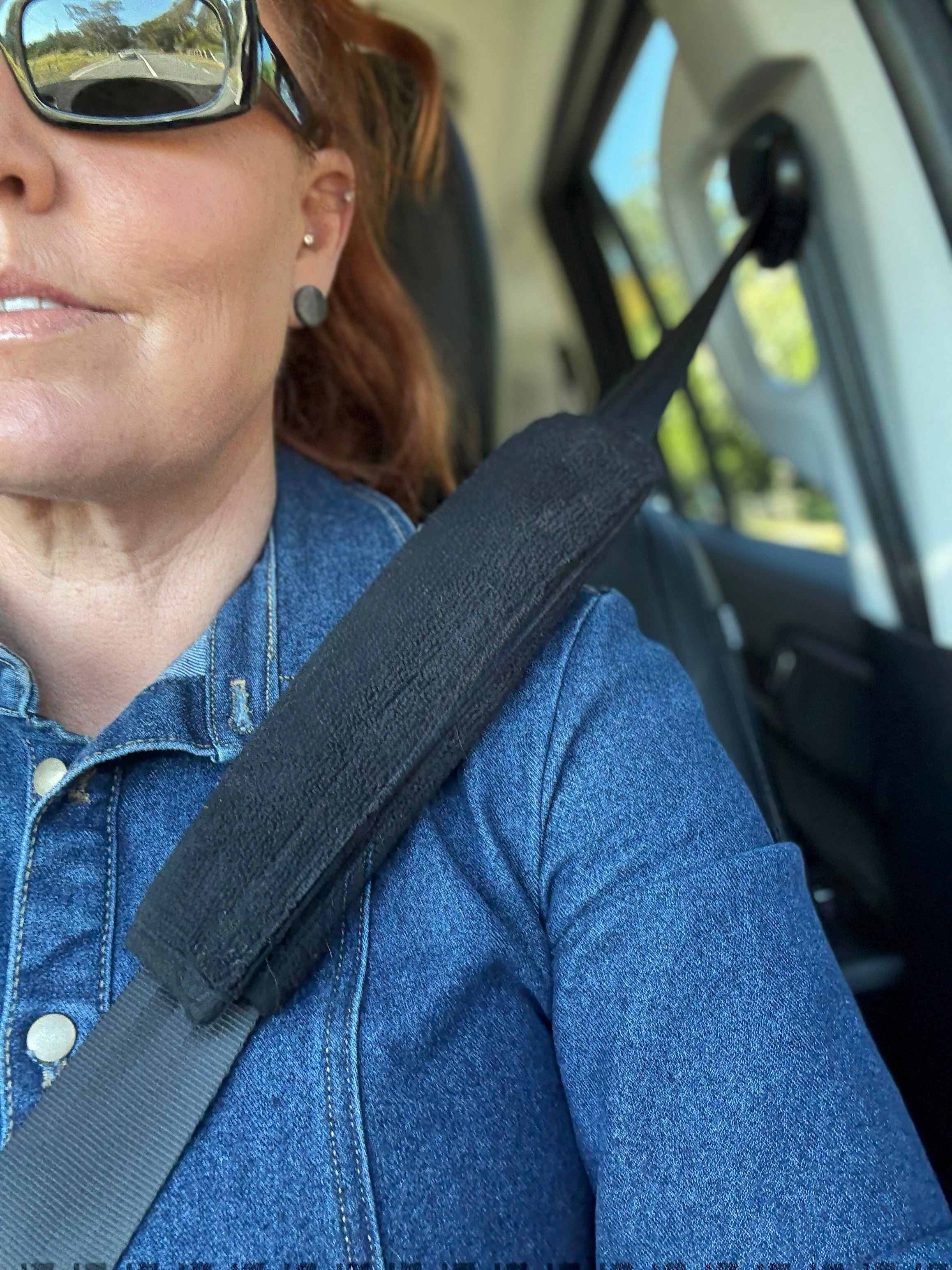 Person wearing a seatbelt protector inside a vehicle with a blurred background