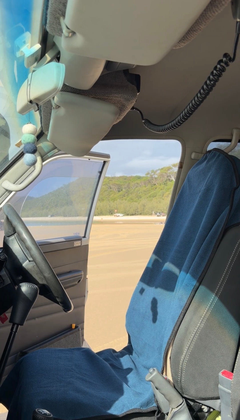 Navy Blue Car Seat Towel on drivers seat with door open on the beach
