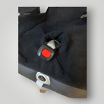 Close-up of a black waterproof child car seat insert with a red buckle on a light gray background.