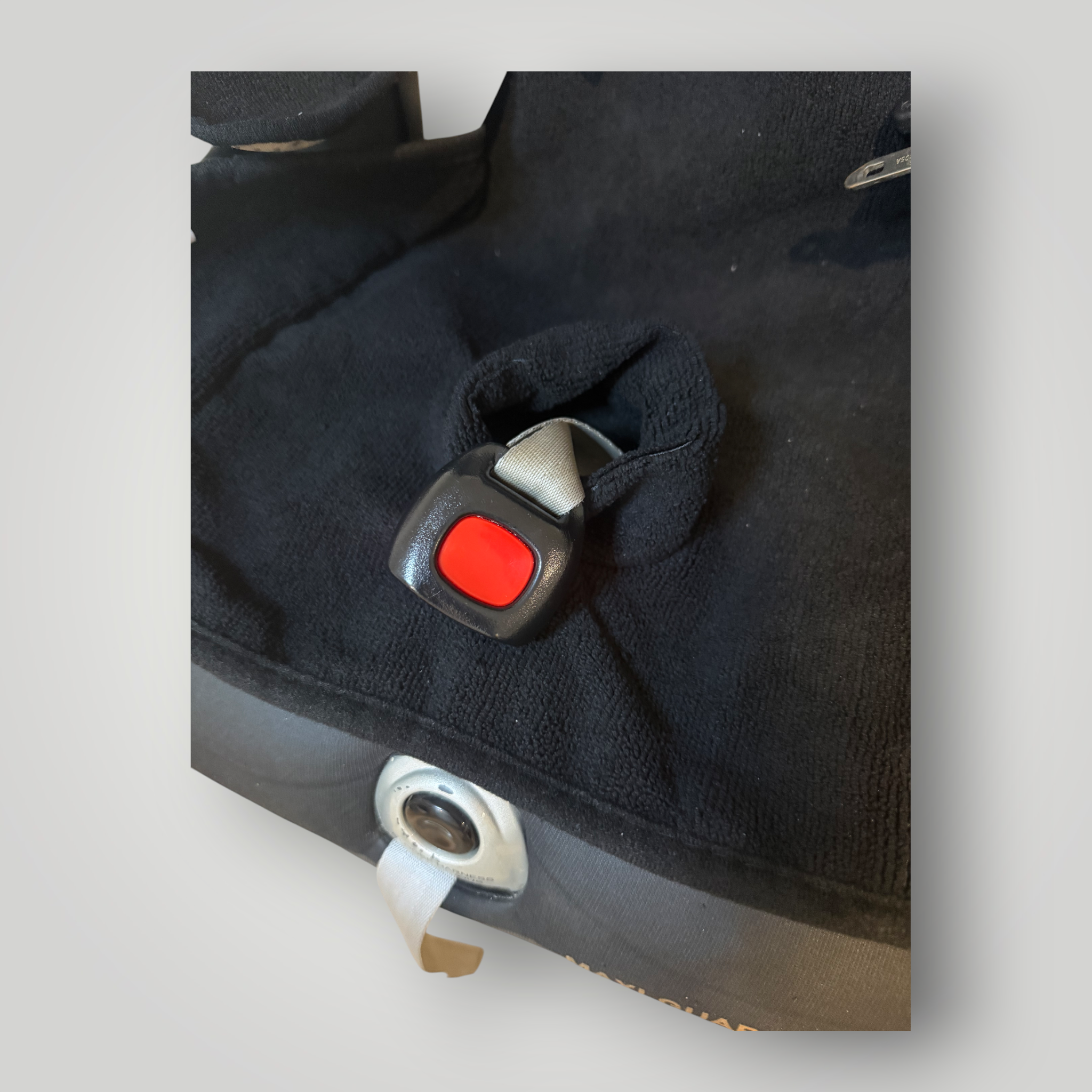 Close-up of a black waterproof child car seat insert with a red buckle on a light gray background.